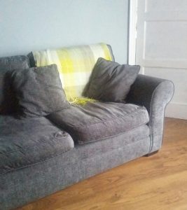 Grey sofa with yellow checked throw.