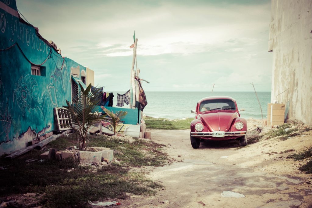 Red VW Beetle by beach - How to save money when purchasing a car.