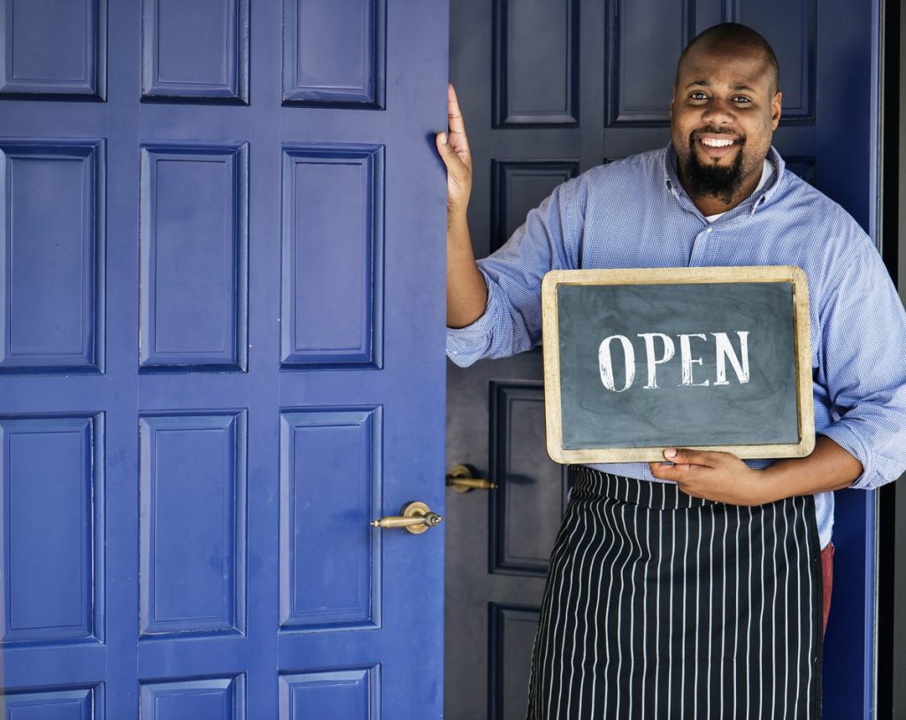 Shop owner holding open sign | 6-point step to creating a franchise 